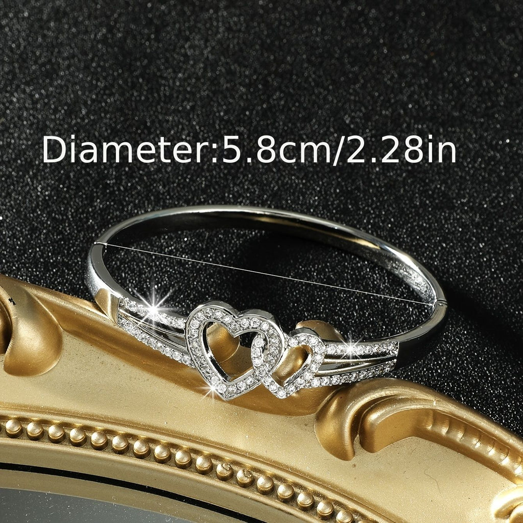 Silver bracelet with heart design on a gold surface, showing size measurement.