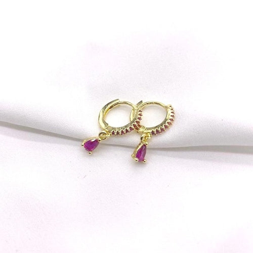 Gold hoop earrings with red gemstones on a white background