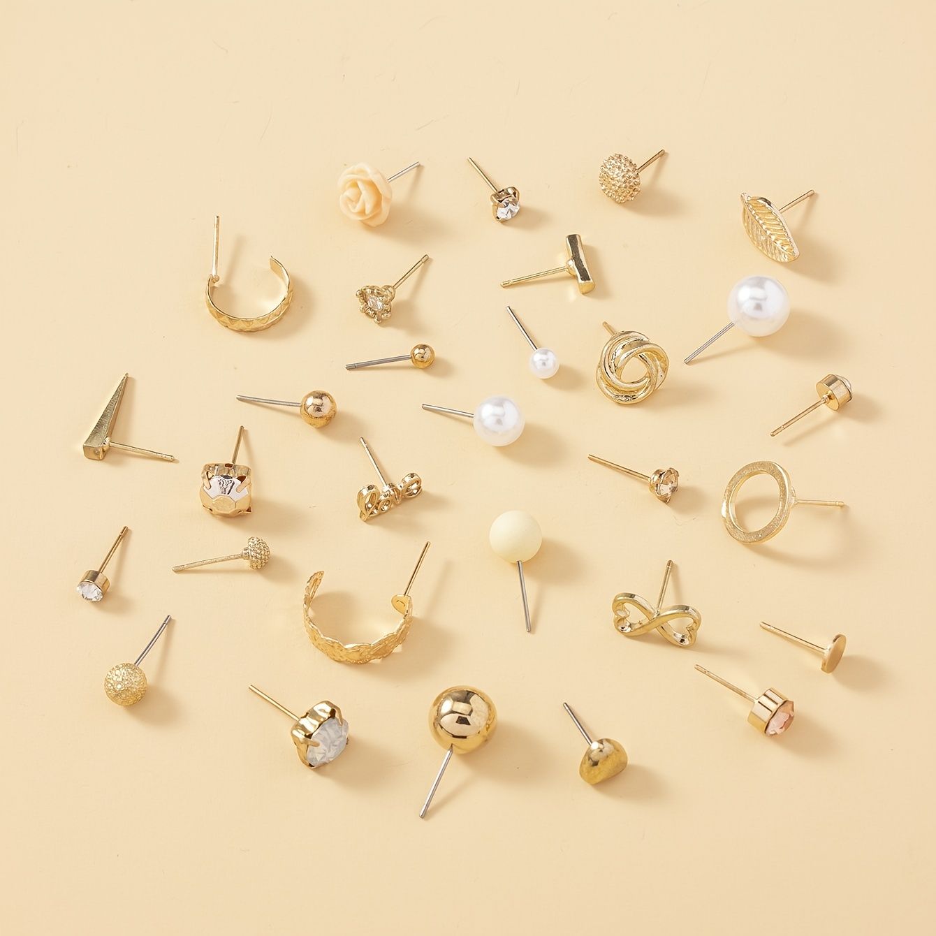 Various gold earrings on a beige background