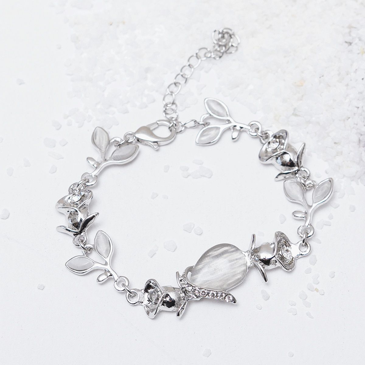 Silver bracelet with leaf and crystal charms on a light background