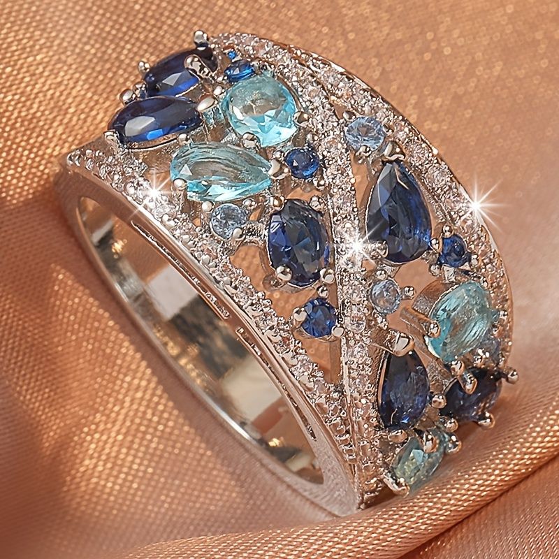 Elegant ring with blue and green gemstones on a beige fabric background