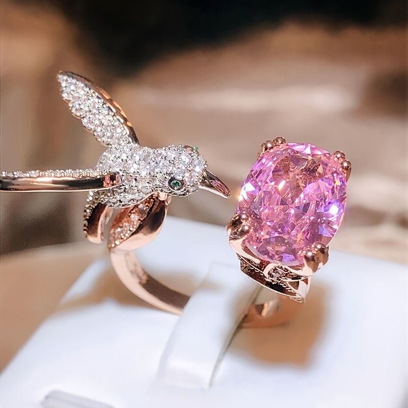 Rose gold ring with pink gemstone on a white stand