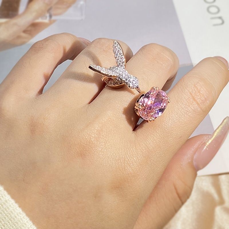 Close-up of a hand wearing two rings with a pink gemstone and diamond accents.