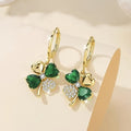 Gold earrings with green gemstones on a beige background