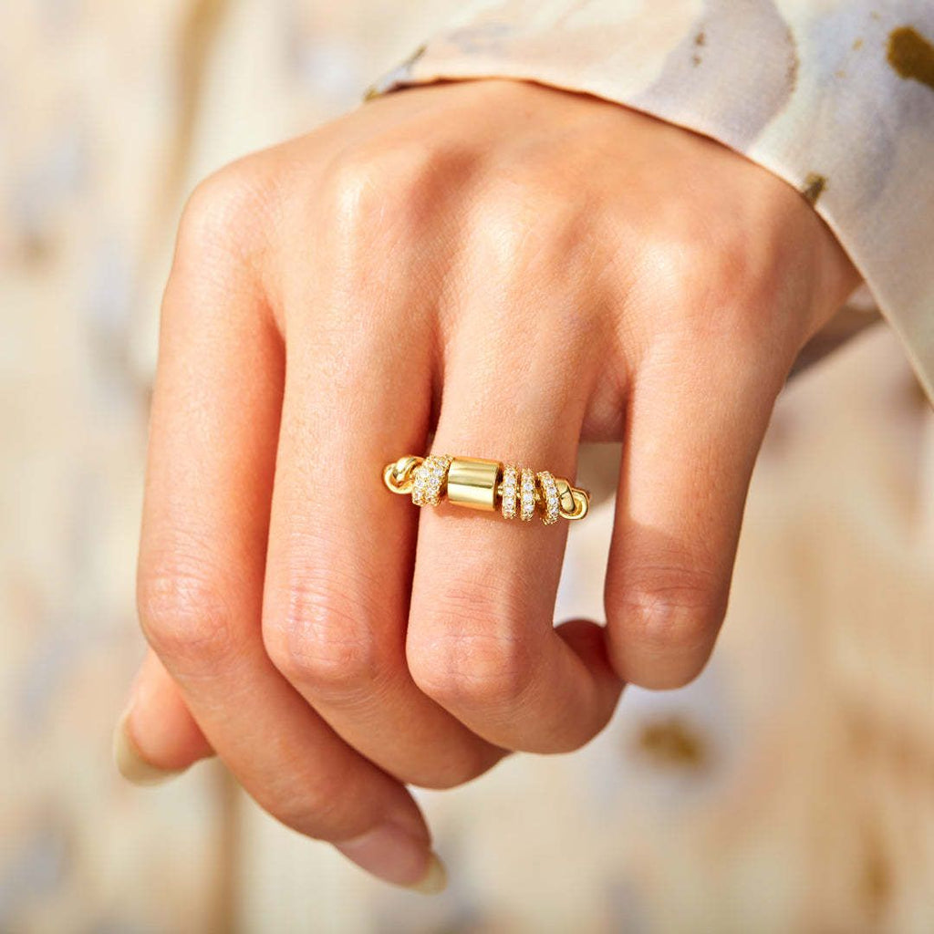 Gold ring with small diamonds on a person's finger against a blurred natural background